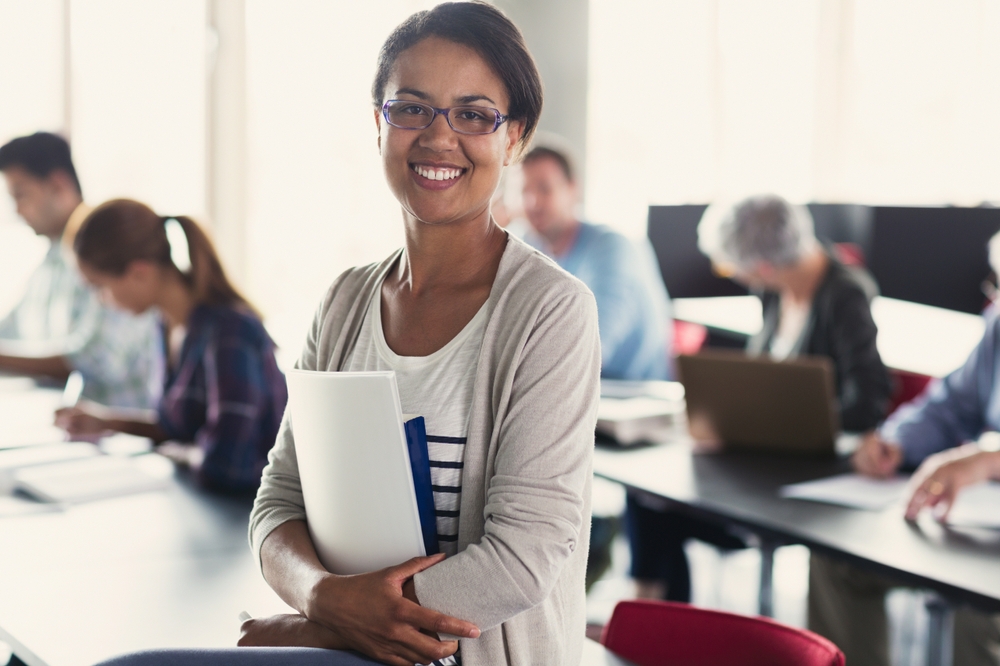 An adult student smiles in front of her classroom.