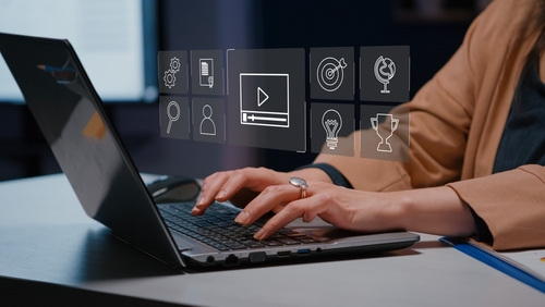 Photo illustration of a woman typing on a laptop with various educational icons above the keyboard.