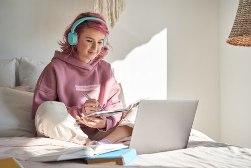Young girl wearing headphones and looking at a computer screen.